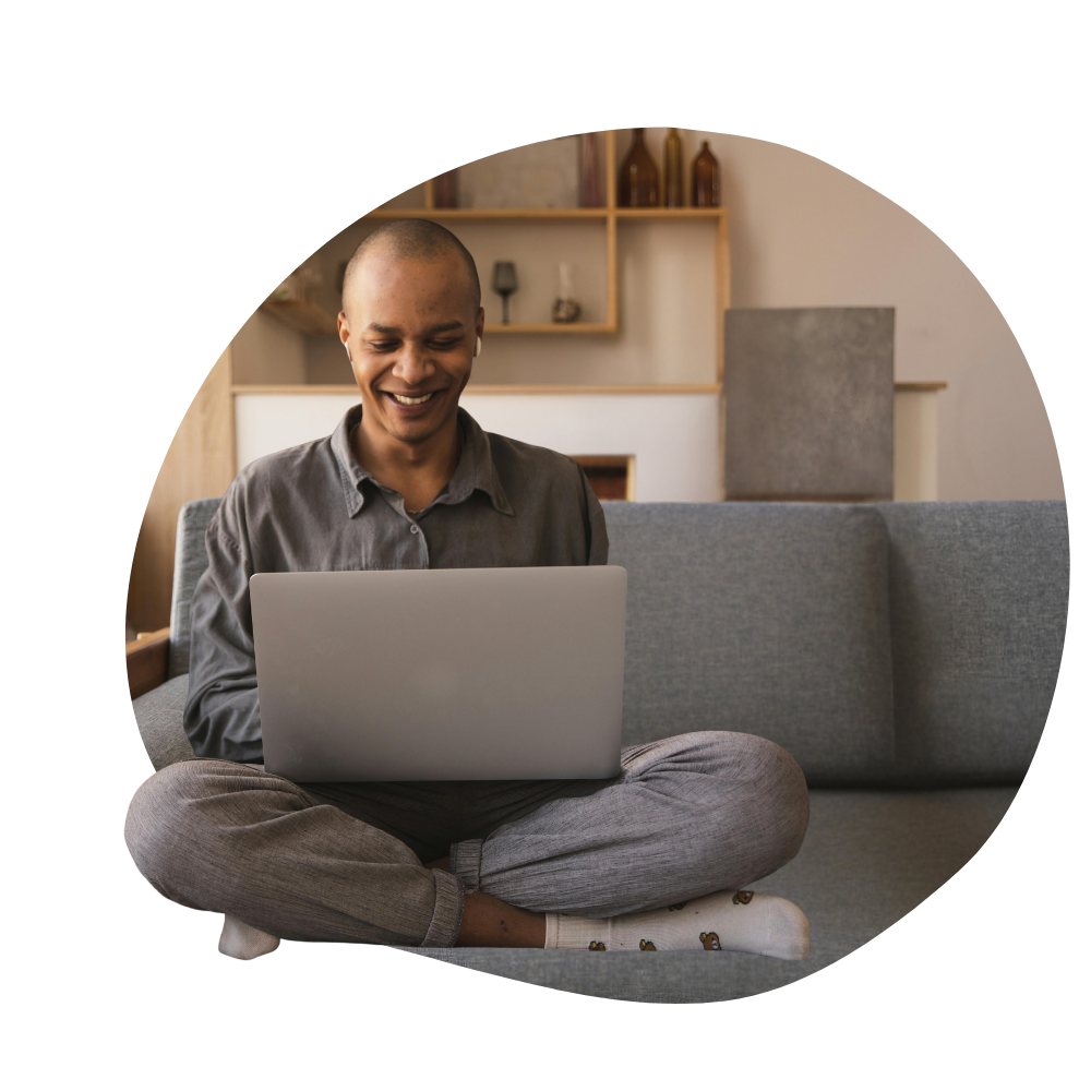 A man sitting on a sofa smiling at his computer
