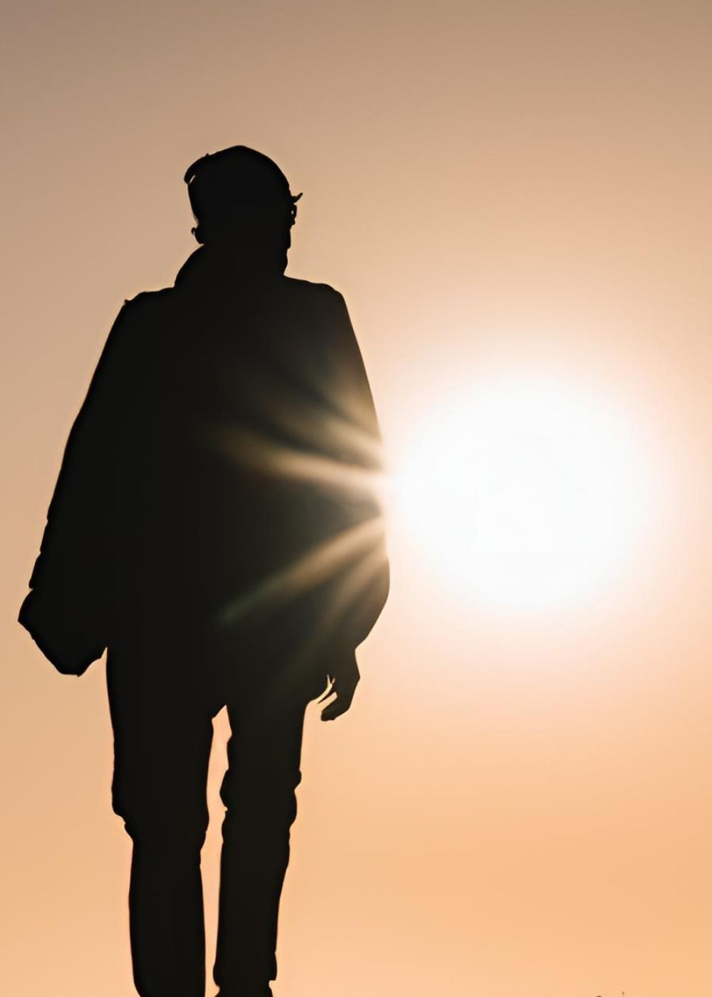 A silhouette of a young man with the sun in the background